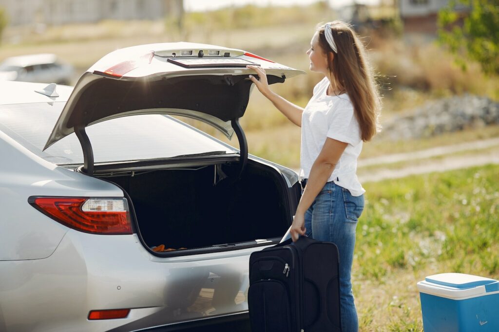 woman loading luggage into car trunk